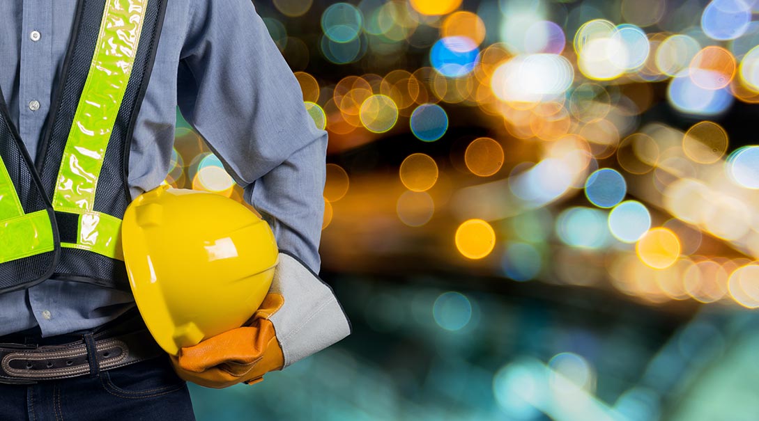 Worker in personal protective equipment holding a hard hat